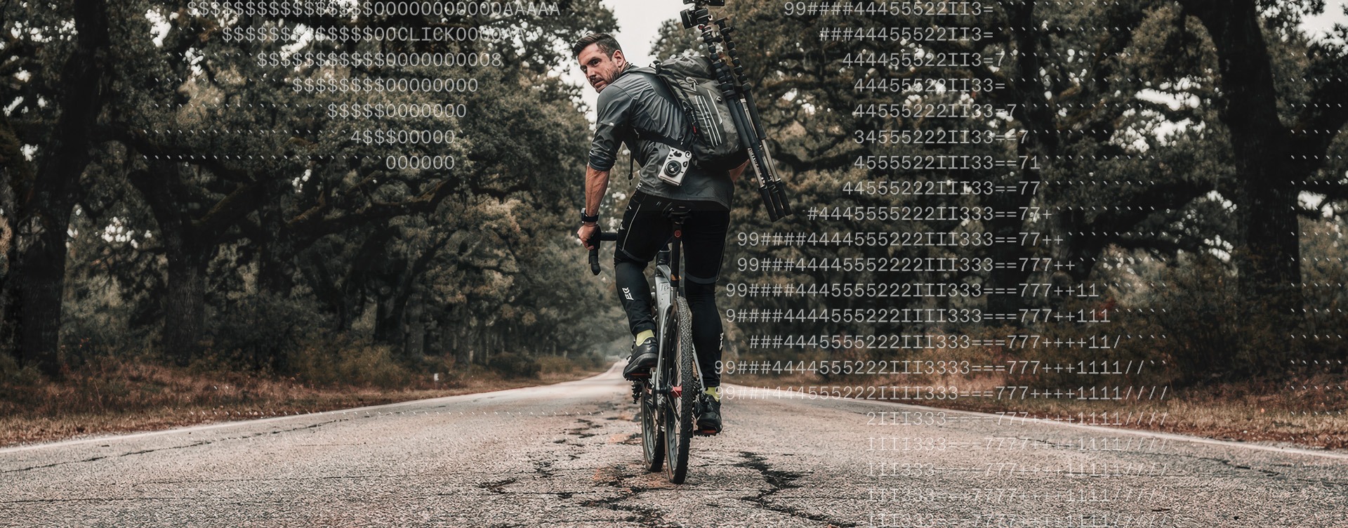 Hartscharfer 16:9 Editorial-Shot: Profi-Fotograf mit Carbon-Stativ auf dem Rücken blickt entschlossen von seinem Bike zurück, düstere Allee-Kulisse, Leica-Ästhetik von The Impression.