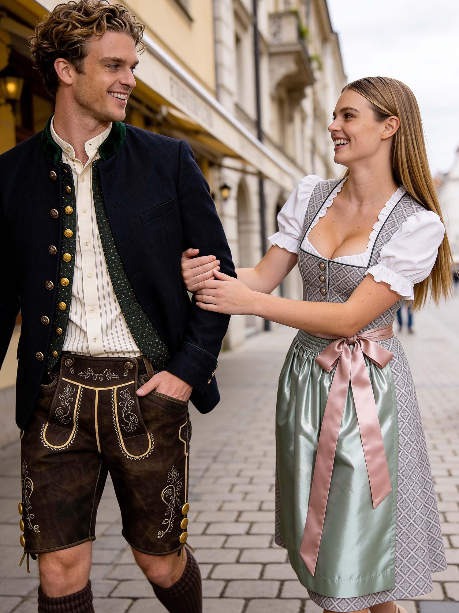 A young couple wearing traditional Bavarian attire playfully walking arm in arm down a cobblestone street in downtown Munich, captured from the side at a low angle as they pass the camera.